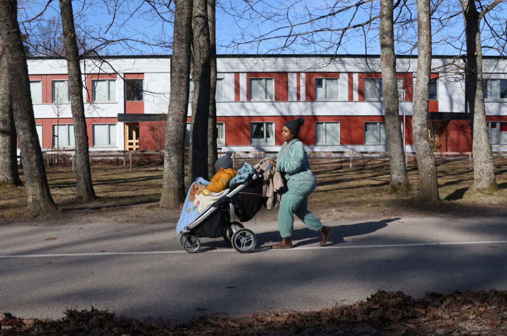 En kvinna med barnvagn går på en gångväg en vårmorgon före lövsprickning.