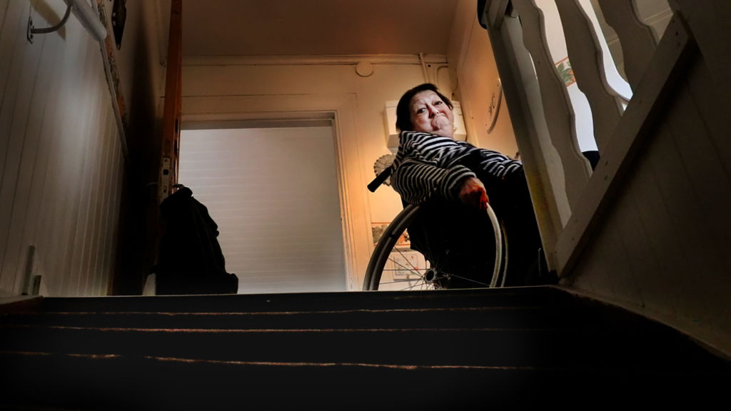 En kvinna sitter i rullstol ovanför en trappa.
