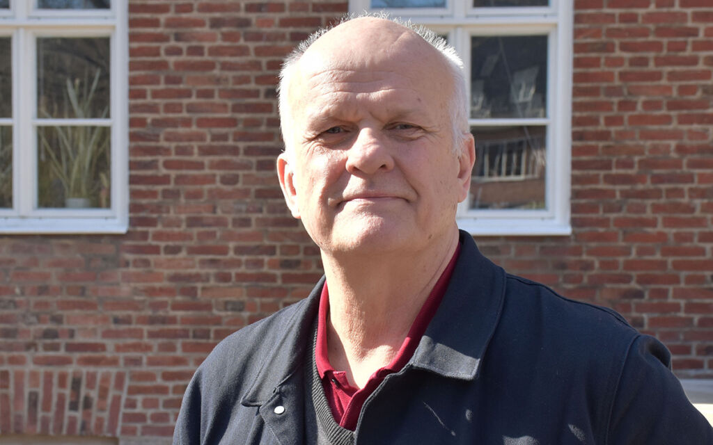 Arne Kristiansen. Foto Lunds universitet En man framför en tegelvägg med vita fönsterkarmar.