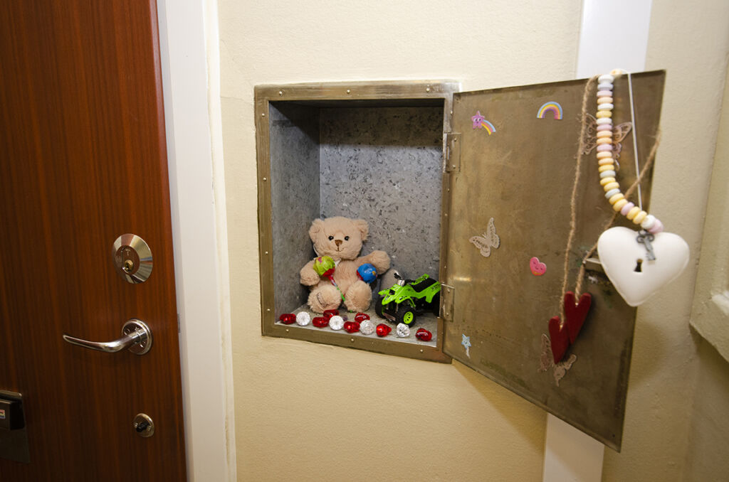 Ett gammalt mjölkskåp intill Nimas ytterdörr har dekorerats med leksaker, godis och hjärtan till minne av femåringen som miste livet i hissolyckan här.