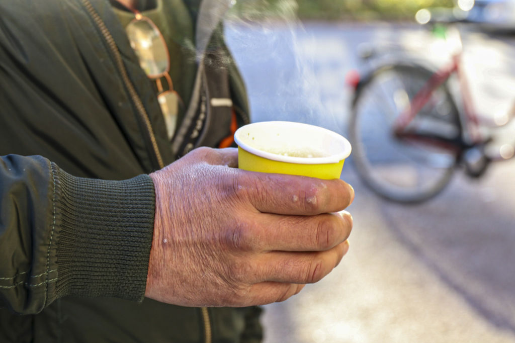 Närbild på en hand som håller en mugg med kaffe. Det ryker ur muggen.