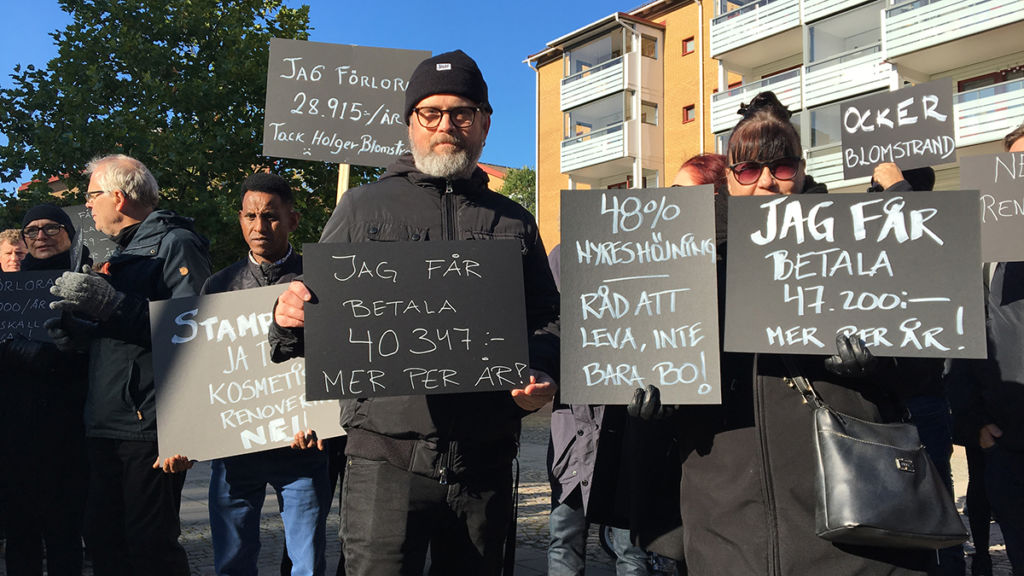 Svartklädda hyresgäster med plakat på Olskrokstorget.